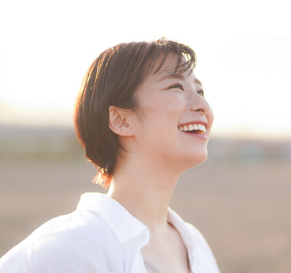 笑顔の女性が野原に立っている様子を捉えた画像